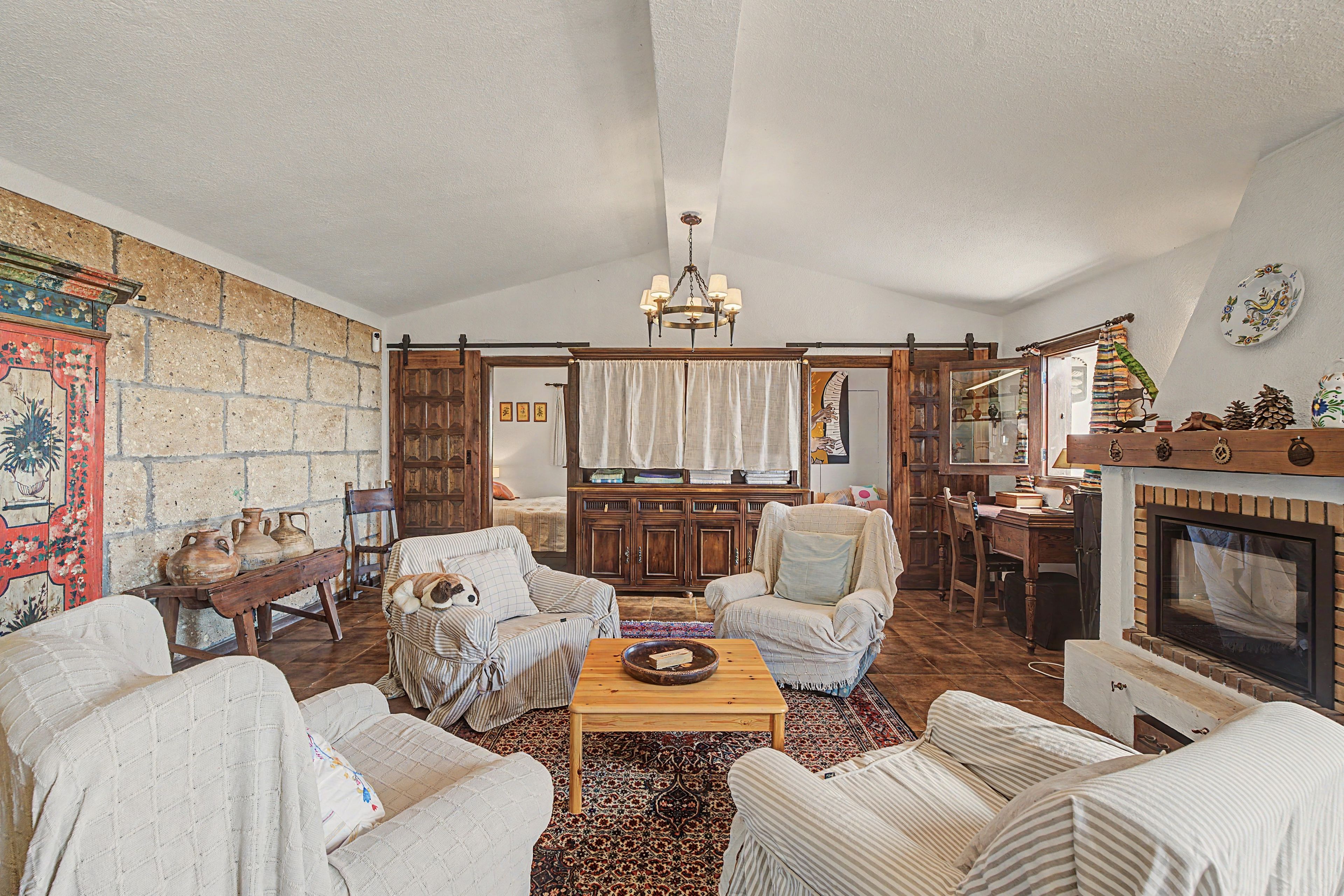 A cozy living room with a fireplace, wooden furniture, and a patterned rug.