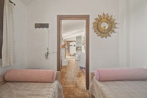 A hotel room with two beds, a mirror, a wall clock, and a view into the dining area. - Casa Bike and Hike Camino Teide: Sea Views, Shared Terrace & Wi-Fi (Vilaflor)