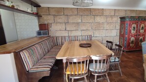 Ein Essbereich mit einem Holztisch, Stühlen, einer gestreiften Couch und einem Möbelkorpus mit Muster.
