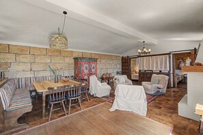 Ein gemütliches Wohnzimmer mit einem Holzesstisch, Stühlen, einer gemusterten Couch, einem dekorativen Schrank und einem Hund.