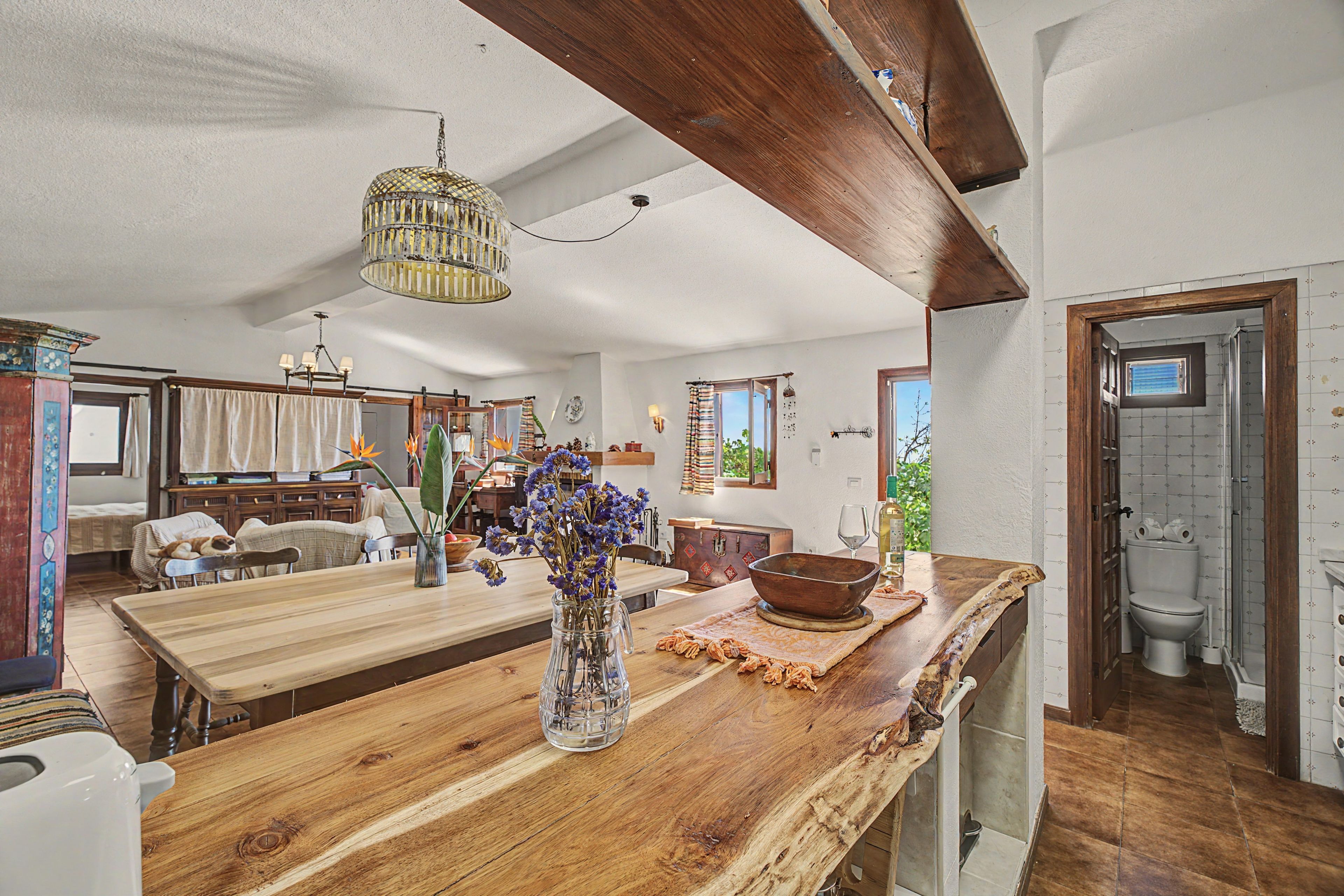 A spacious kitchen with a wooden island, a hanging light fixture, and a view to the dining area.