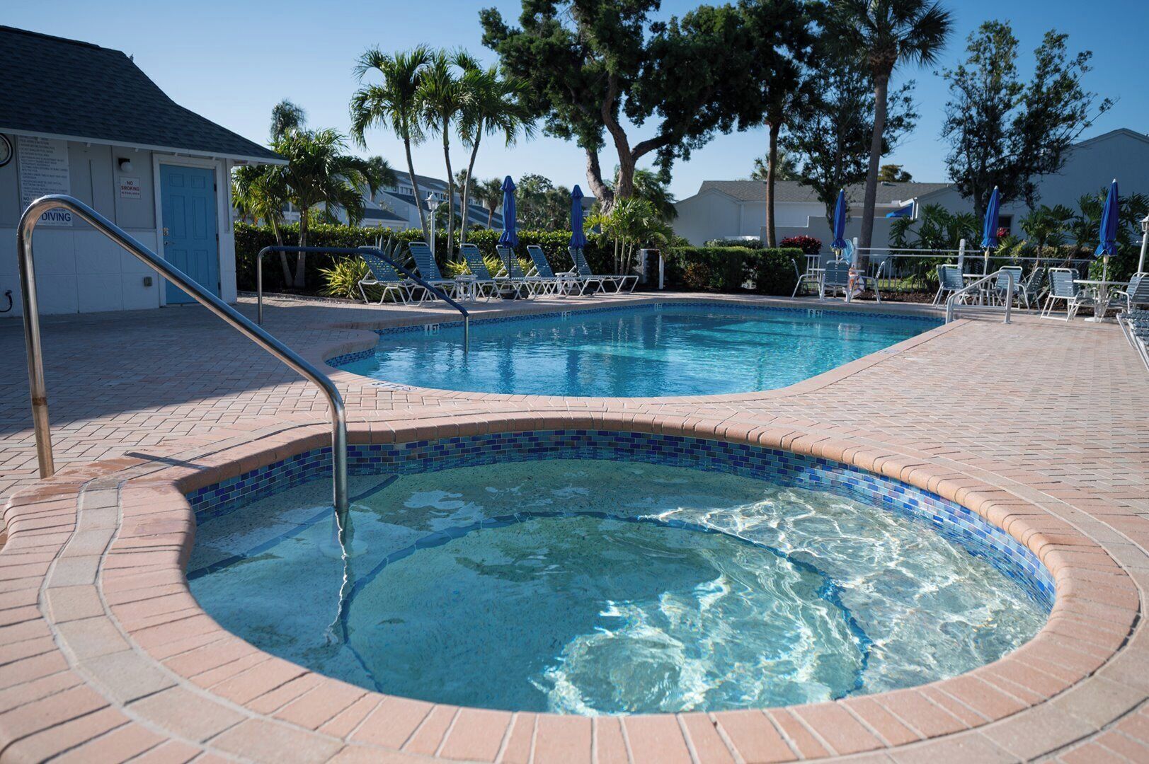 Une piscine avec un jacuzzi, des chaises longues et des palmiers.
