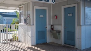 L’entrée du spa, située sur Waterside Lane, est reconnaissable à ses portes bleues portant les inscriptions « FEMMES » et « HOMMES », ainsi qu’à la présence d’un défibrillateur automatisé externe (DAE) et d’un panneau affichant les règles du spa.
