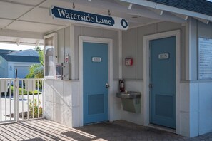 Eingang zum Spa an der Waterside Lane mit blauen Türen, auf denen 'FRAUEN' und 'HERREN' steht, einem Defibrillator und einem Schild mit Spa-Regeln.