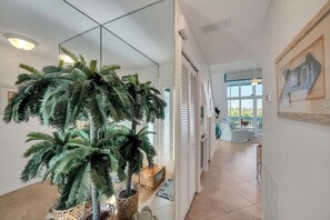Ein modernes Interieur mit einer großen k ünstlichen Palme, einer Glastür, die auf einen Balkon führt, und einem gerahmten Schild an der Wand.