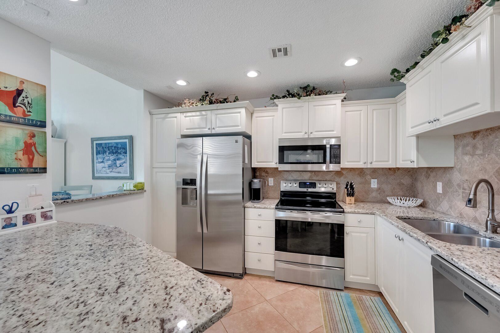A modern kitchen with white cabinetry, stainless steel appliances, and a granite countertop.