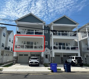 Un immeuble résidentiel de deux étages, doté d’un garage, d’un balcon et d’une allée où sont garées des voitures.
