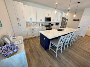 A modern kitchen with white cabinets, a central island, and pendant lighting. - 158 E Garfield Ave  Unit 106 Wildwood, NJ (Wildwood)