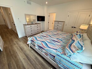 Une chambre à coucher avec un lit, une commode, un téléviseur et une porte.