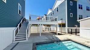 Zona residencial con piscina, terraza cubierta y escalera que sube a un segundo piso.