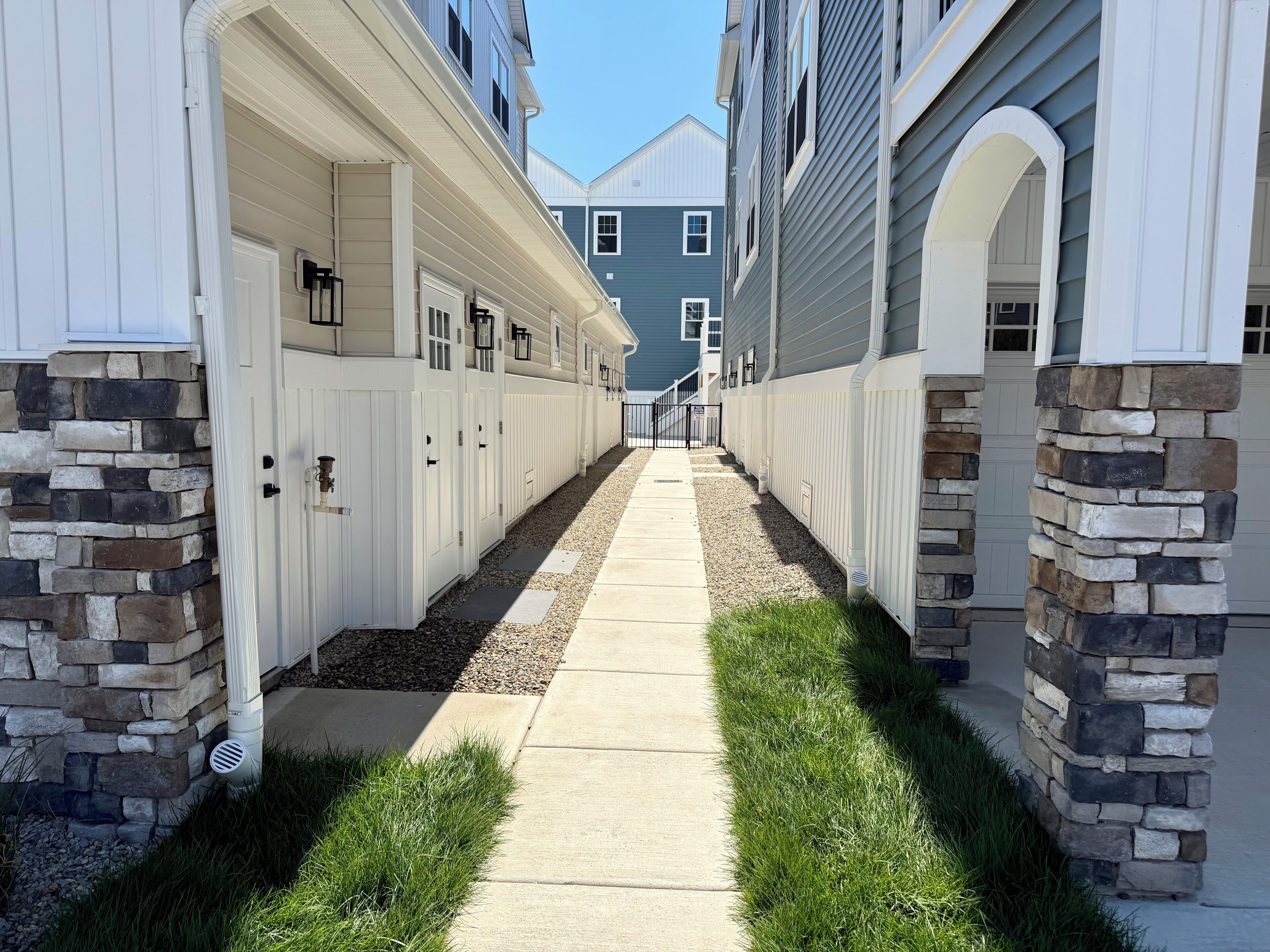 Una hilera de casas urbanas con detalles de piedra, un camino central y cielo despejado.
