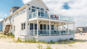 A two-story beachfront house with a balcony, a covered patio, and a view of the beach. - Hamptons Best Beach House. On the Sand. Sleeps 8. Parking. Porch. Beach Gear (Hampton)