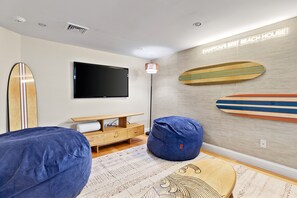 Ein modernes Wohnzimmer mit Flachbildfernseher, Holzsurfbrettern an der Wand und einem Sitzsack.