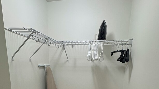 Un lavadero con un tendedero de metal, una plancha y un perchero para ropa.