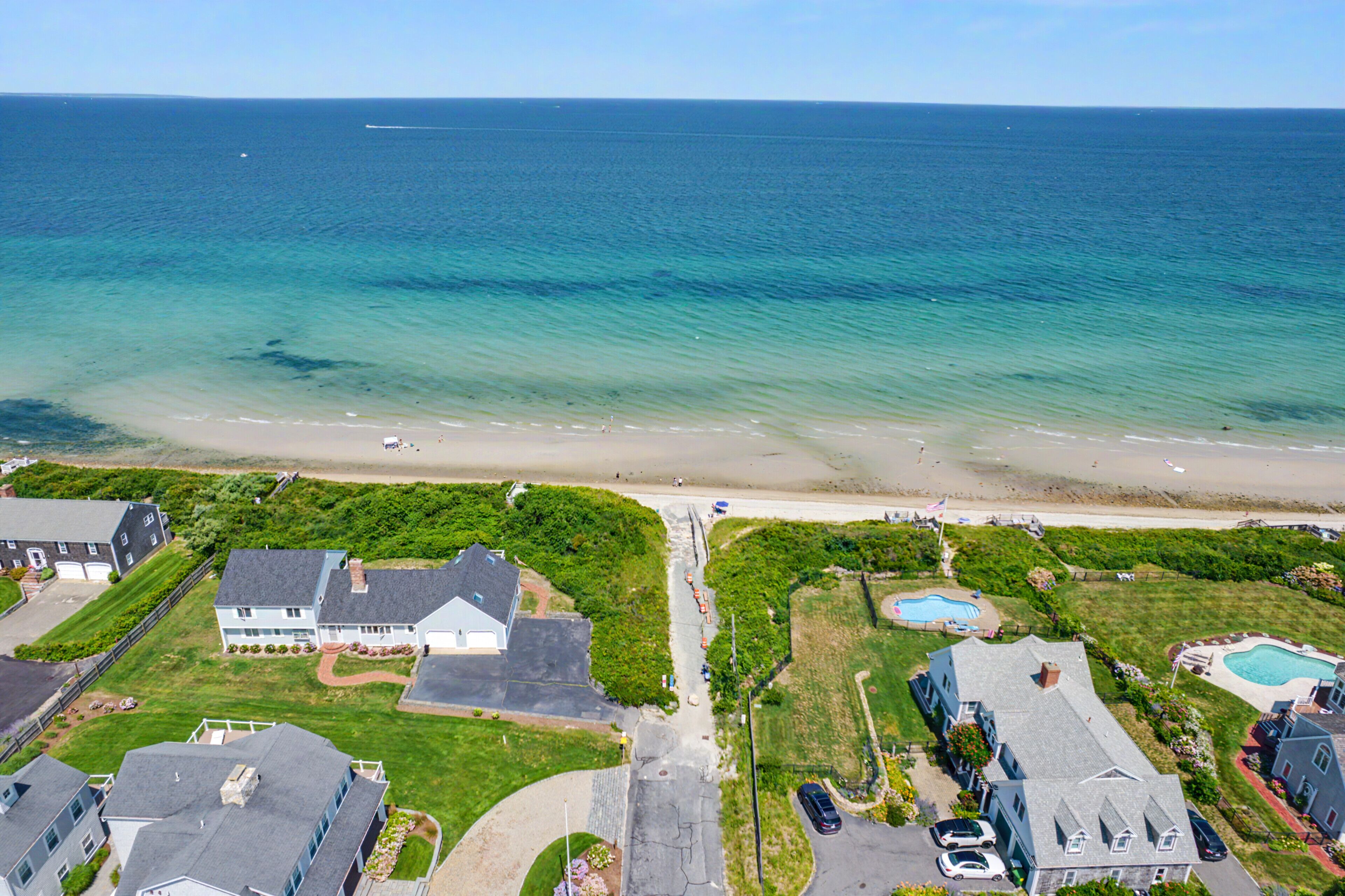 A coastal residential area with houses, a swimming pool, and a beach.