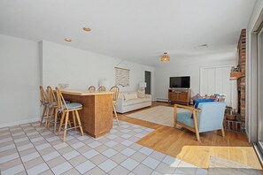 Ein modernes Wohnzimmer mit Essbereich, einer Couch, einem Fernseher und einem Kamin.