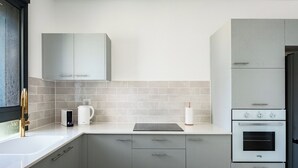A modern kitchen with grey cabinets, a built-in oven, and a coffee maker. - Elegant 4BR Stay l Balcony & Mamad (Bat Yam)