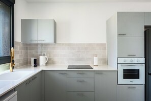 Eine moderne Küche mit grauen Schränken, einem eingebauten Backofen und einer Kaffeemaschine.