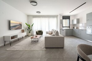 Ein modernes Wohnzimmer mit einer Couch, einem Couchtisch und einem Fernseher an der Wand.