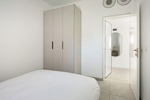 Ein Schlafzimmer mit einem Bett, einem Kleiderschrank, einer Tür zu einem Badezimmer und einem Spiegel.