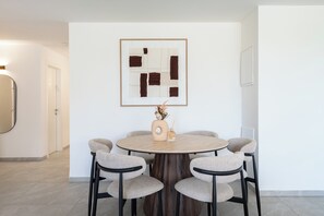 Ein Essbereich mit einem runden Tisch, sechs Stühlen und einem gerahmten, abstrakten Kunstwerk an der Wand.
