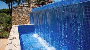 Ein Schwimmbecken mit einer Steinmauer und einem Wasserfall.