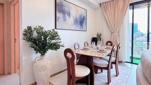 Comedor moderno con una mesa grande, sillas, una planta en maceta y vistas a la ciudad a través de amplios ventanales.