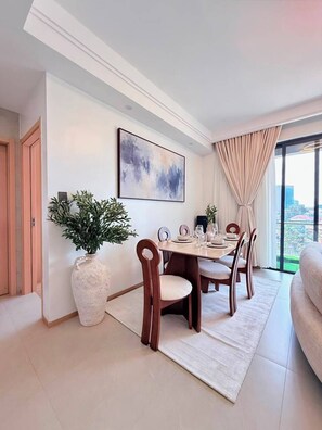 A modern dining room with a large table, chairs, a potted plant, and a city view through large windows. - The Velvet Nook Rooftop Pool and Gym (Nairobi)