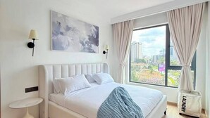A modern bedroom with a large bed, a city view, a painting on the wall, and a laundry bag. - The Velvet Nook Rooftop Pool and Gym (Nairobi)