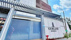 A tall, modern building with a prominent entrance gate and a sign reading 'GEMLAND RESIDENCE'. - The Velvet Nook Rooftop Pool and Gym (Nairobi)
