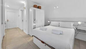 Una habitación de hotel con cama, lámparas de noche, armario y puerta del baño.