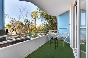 A balcony with artificial grass, two wicker chairs, and a white railing. - Home Holidays 114 (CN)