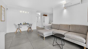 Una sala de estar moderna con un sofá seccional gris, una mesa de comedor con sillas y una mesita negra.