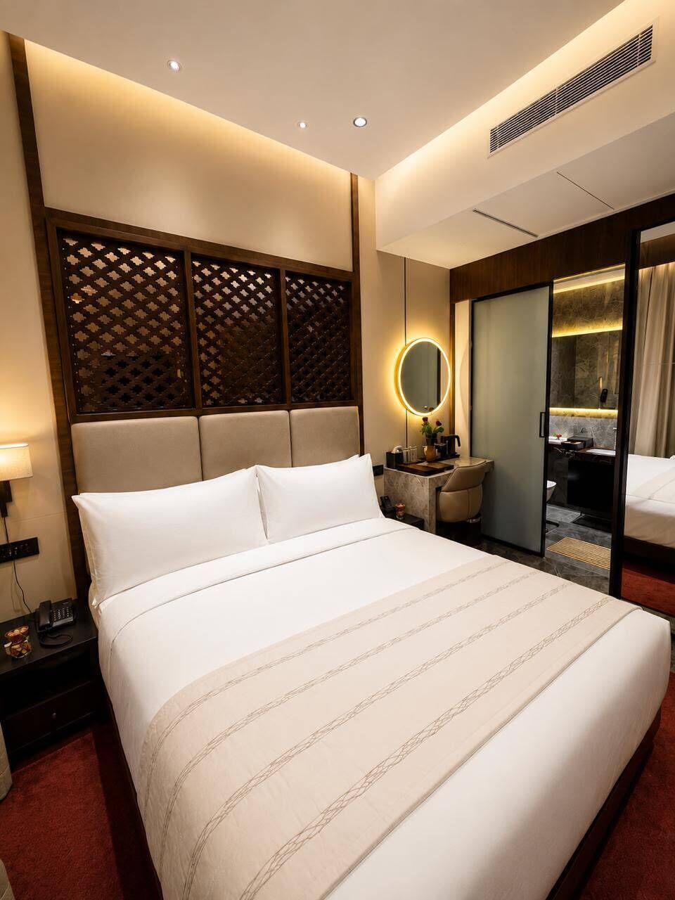 Una habitación de hotel con una cama grande, una mesita de noche y un espejo.