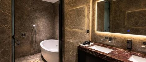 A modern bathroom with a freestanding bathtub, a large mirror, and a marble countertop.