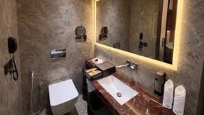 A modern bathroom with a marble vanity, a large mirror, and a toilet.