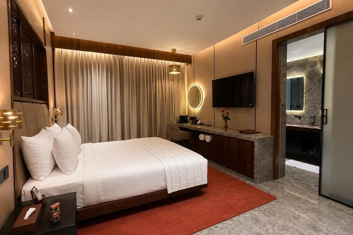 Une chambre d’hôtel moderne équipée d’un lit, d’un bureau, d’un miroir et d’une salle de bain avec douche.
