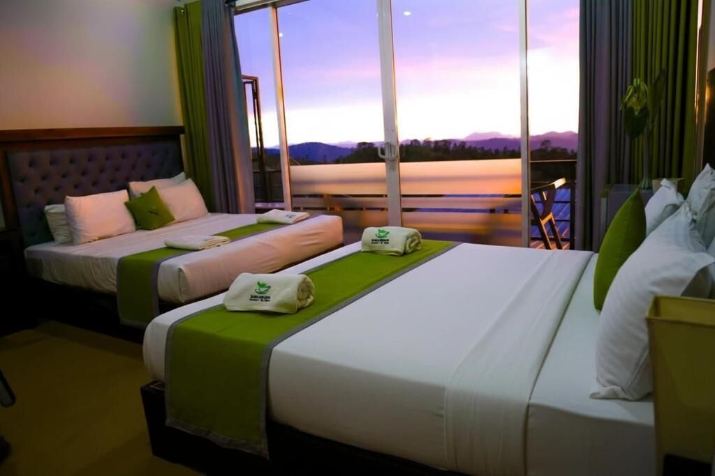 A hotel room with two beds, a large window with a view of the mountains, and a balcony.