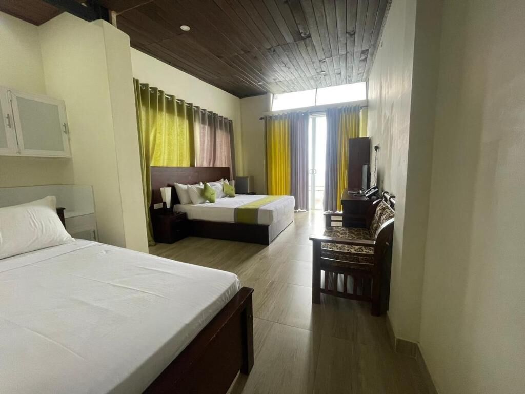 A hotel room with two beds, a desk, a chair, and a television.