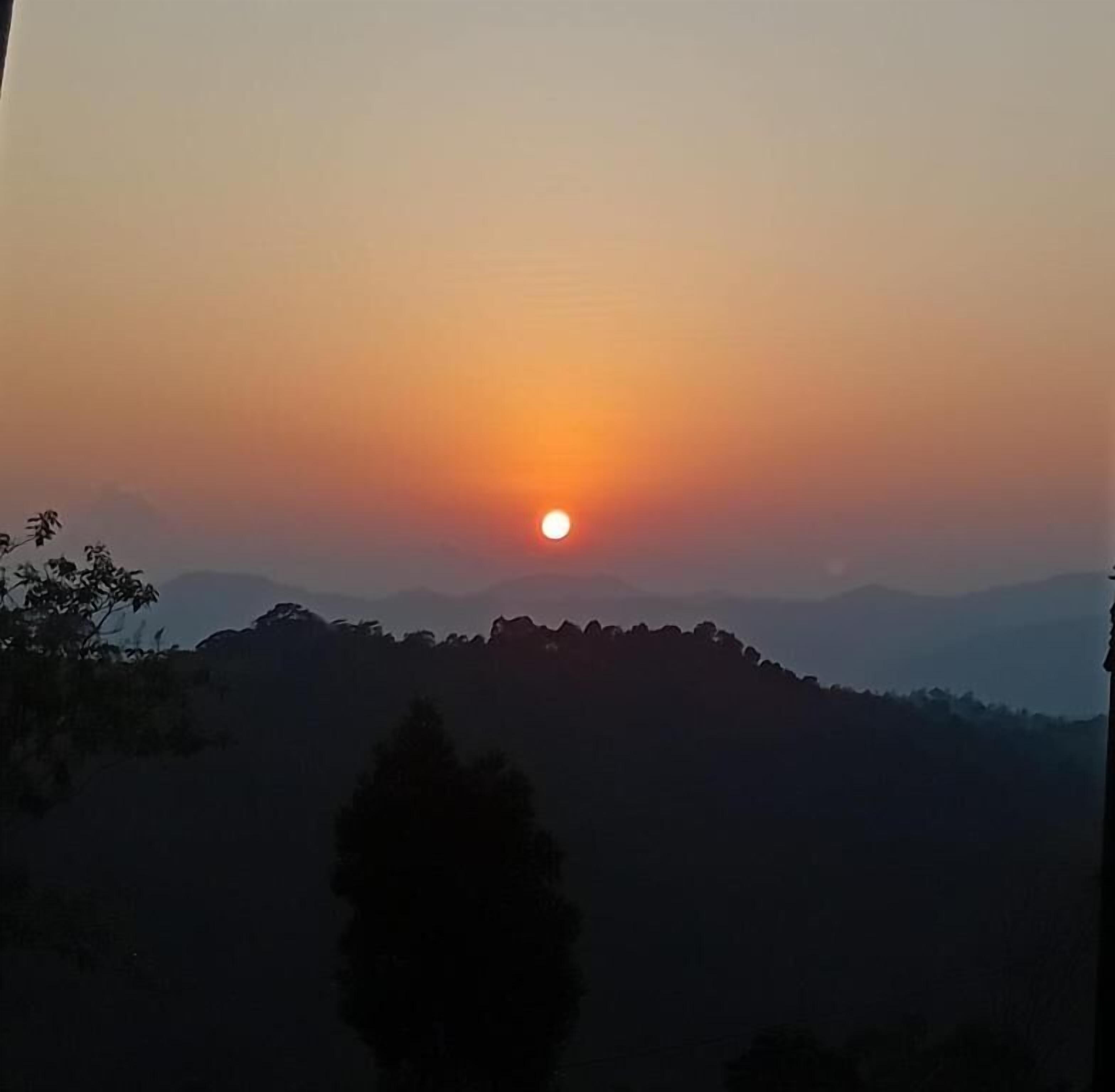 Ein Sonnenuntergang über einer hügeligen Landschaft.