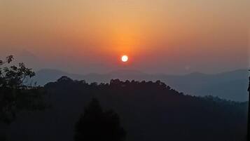 Ein Sonnenuntergang über einer hügeligen Landschaft.