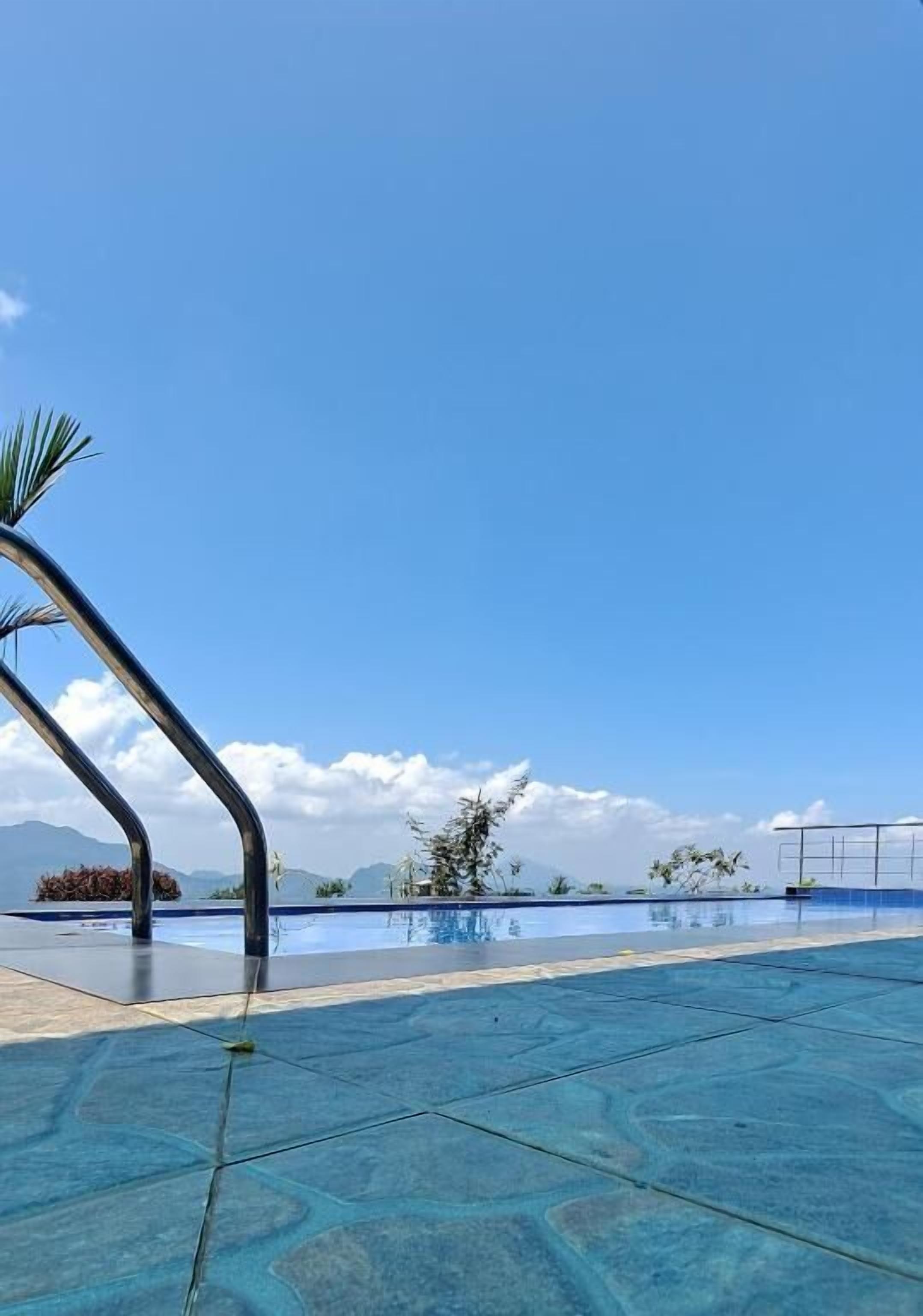 Cel blau clar sobre una piscina amb barana metàl·lica.