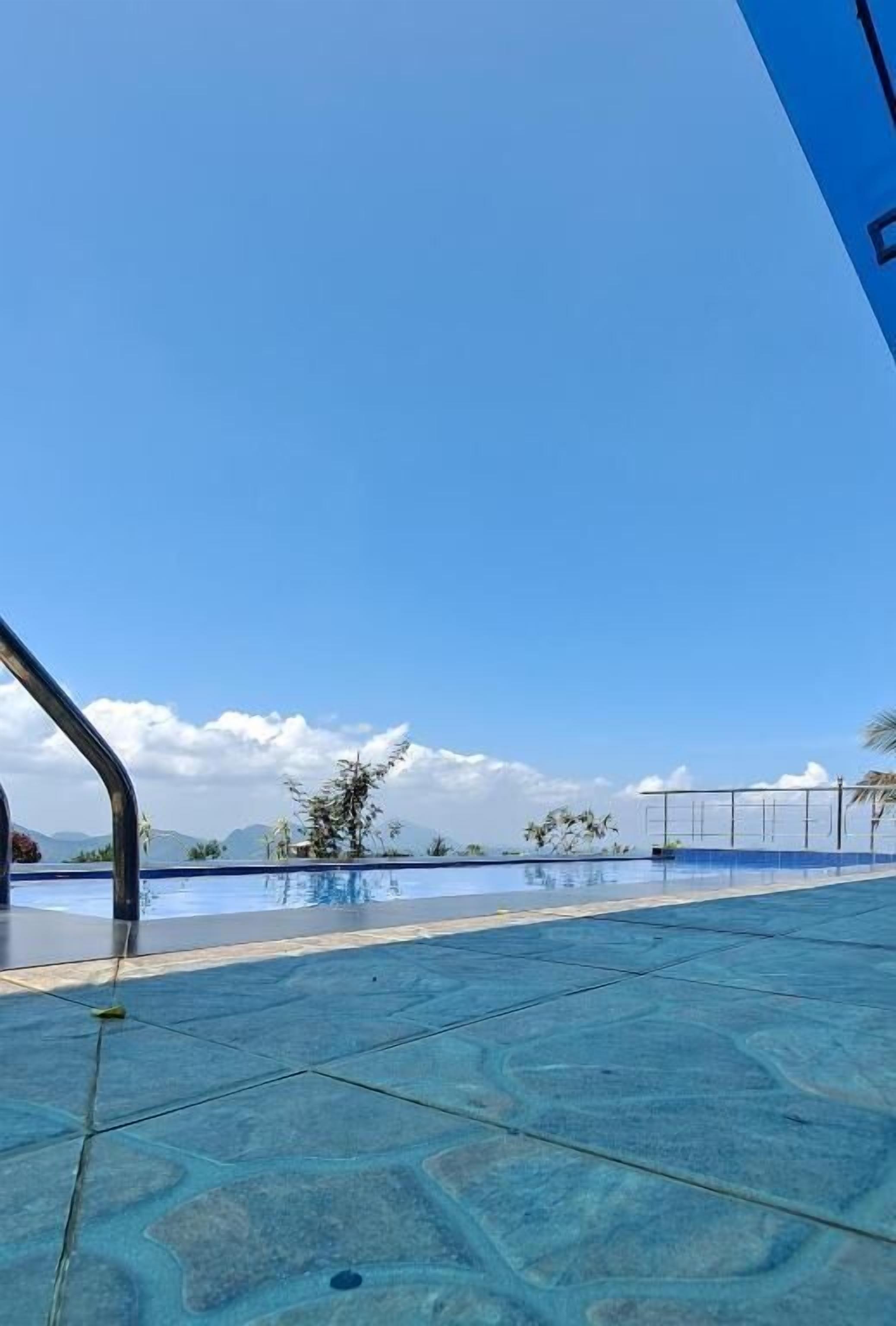 A clear blue sky above a swimming pool with a tiled floor.