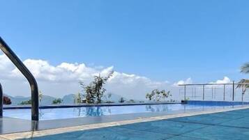 A clear blue sky above a swimming pool with a tiled floor.