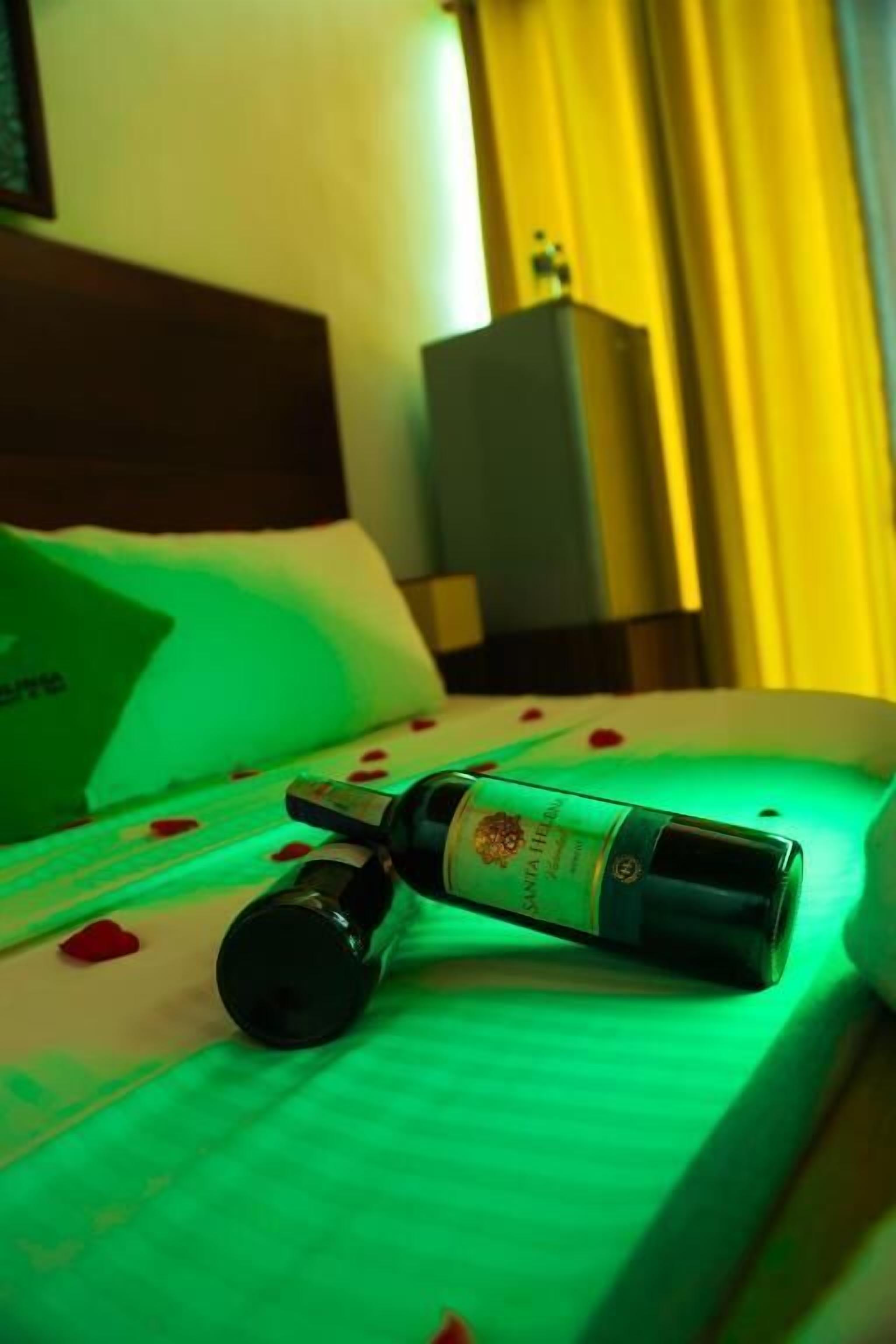 Eine Weinflasche auf einem Bett, beleuchtet von grünem Licht.