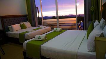 Habitación de hotel con dos camas, un ventanal con vistas a las montañas y un balcón.