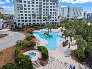 A hotel with a swimming pool, palm trees, and a view of Hilton buildings. - 4th-Floor Studio | Walk to Beach | Pool, Beach Tram | Luau II 6421, Sandestin (Miramar Beach)