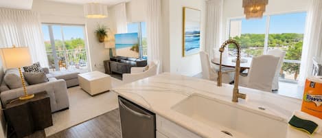 A modern living room with a sofa, a dining table, and a kitchen area with a sink.
