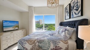 Un dormitorio con cama, televisor en una cómoda, candelabro y obra de arte en la pared.