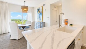 Cocina moderna con encimera de mármol, horno empotrado y vistas al exterior.